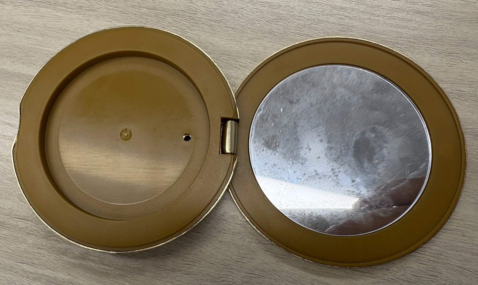 Open compact case with the plastic recess on the left, the mirror on the right, and the aluminum shell around the outside